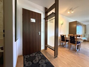 A wooden door with a sign, a black floral rug, a dining area with chairs and a table, and a ceiling fan. - Royal 51 # 4-bed apartment, Bad, WC 4-Bettwohnung, Bad, WC by Interhome (Leukerbad)