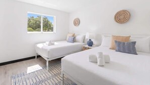Une chambre d’hôtel avec deux lits, une fenêtre, un élément de décoration circulaire fixé au mur et une table de chevet avec une lampe.