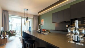 Une cuisine moderne dotée d’un îlot central, de tabourets de bar, d’un coin repas avec un canapé et des chaises, et offrant une vue à travers une porte vitrée.