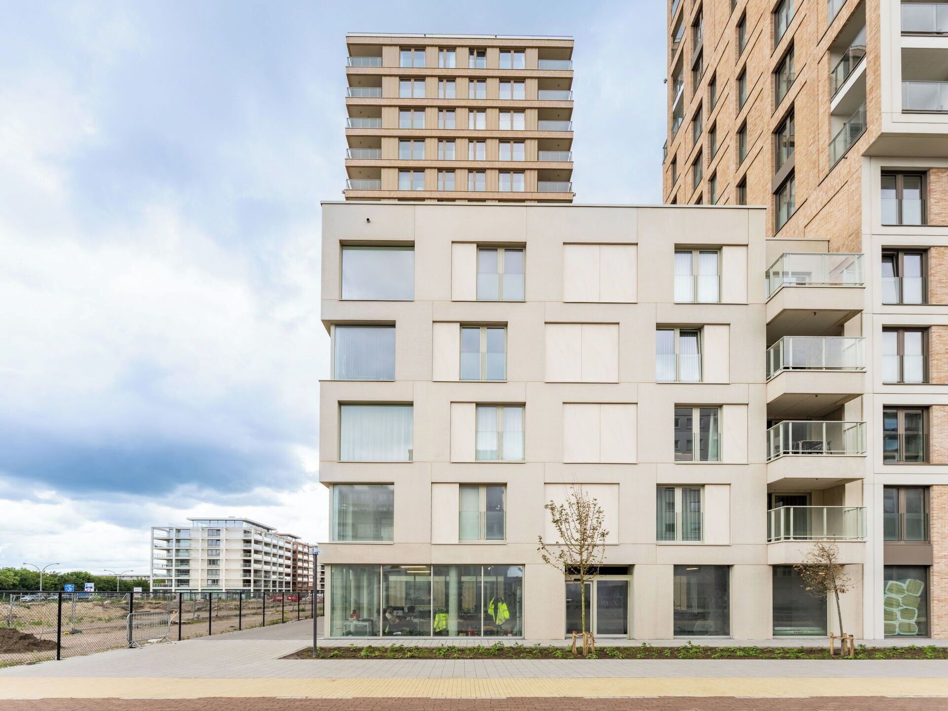 A modern multi-story residential building with balconies, large windows, and a flat roof.