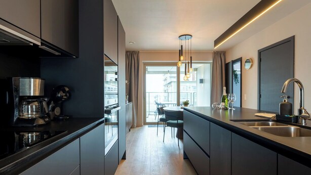 Une cuisine moderne dotée d’un îlot central, d’appareils électroménagers en acier inoxydable et donnant sur la salle à manger.