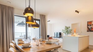 Un espace repas moderne avec une table en bois, des chaises et des luminaires suspendus.
