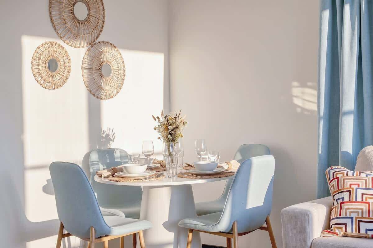 Un coin repas comprenant une table ronde, quatre chaises et des œuvres d’art décoratives accrochées au mur.