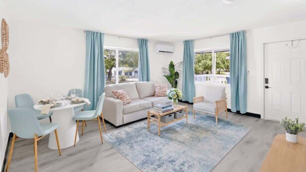 Een moderne woonkamer met een bank, stoelen, een salontafel en een eettafel.