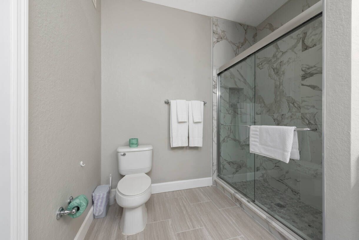 Ein Badezimmer mit Toilette, einer Duschkabine aus Glas und einem Handtuchhalter.