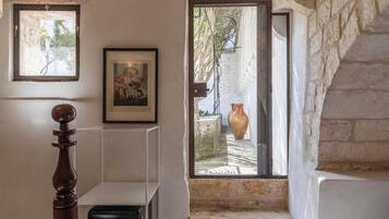 A staircase with stone walls, a wooden balustrade, a framed picture, and a large vase in the background.