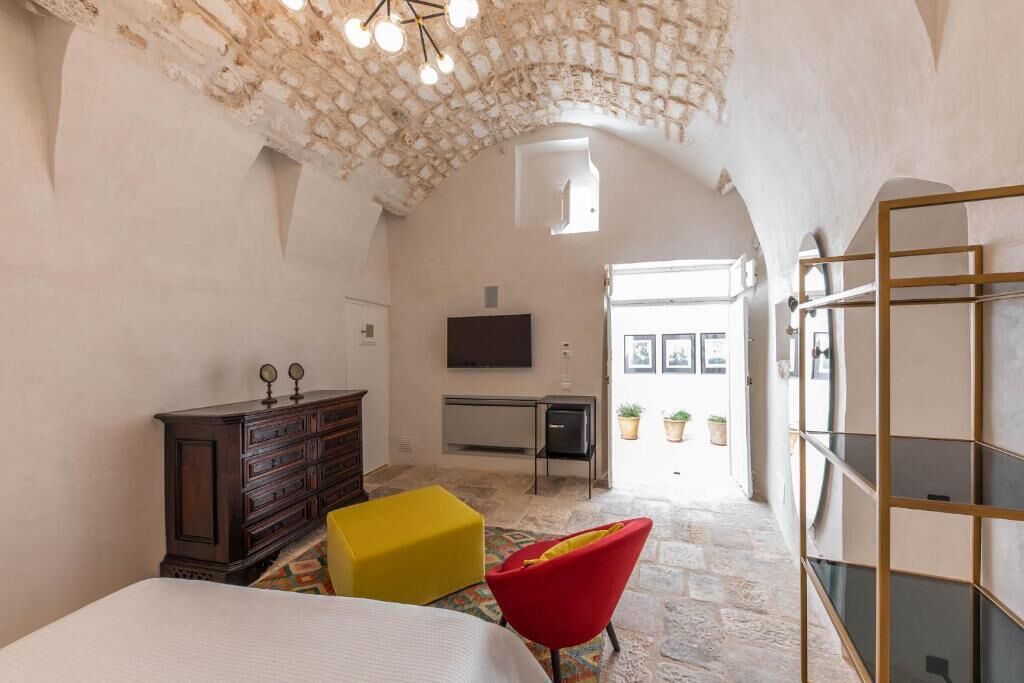 A bedroom with a stone ceiling, a bed, a dresser, a TV, and a desk.