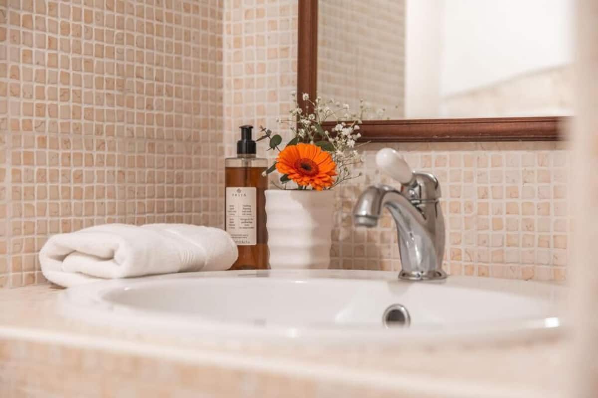 A bathroom with a sink, a mirror, a towel, and a bottle of lotion.