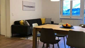 Ett modernt vardagsrum med en matplats, en soffa och ett fönster med utsikt.