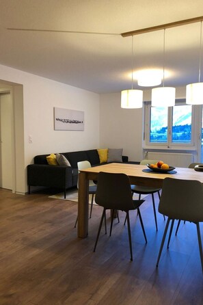 A modern living space with a dining area, a sofa, and a window with a view. - Perle "Balmhoru" # 5-bed apartment, Dusche, WC 5-Bettwohnung, Dusche, WC by Interhome (Leukerbad)