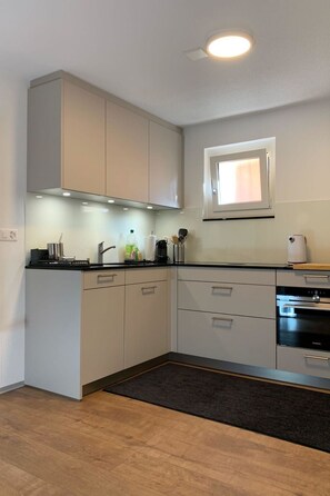 A modern kitchen with built-in appliances, a window, and a dark rug. - Perle "Balmhoru" # 5-bed apartment, Dusche, WC 5-Bettwohnung, Dusche, WC by Interhome (Leukerbad)