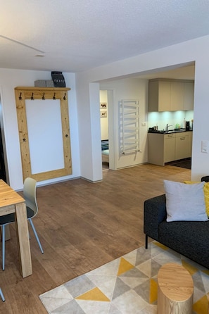 A modern living room with a sofa, a dining table, and a kitchen in the background. - Perle "Balmhoru" # 5-bed apartment, Dusche, WC 5-Bettwohnung, Dusche, WC by Interhome (Leukerbad)
