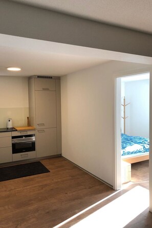 A compact kitchen with modern appliances, a wooden countertop, and a black rug. - Perle "Balmhoru" # 5-bed apartment, Dusche, WC 5-Bettwohnung, Dusche, WC by Interhome (Leukerbad)