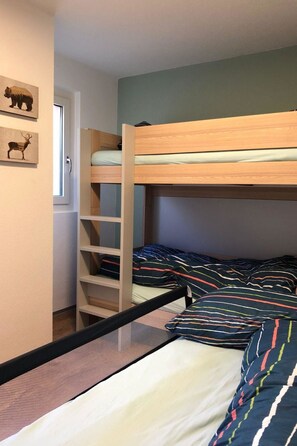 Un letto a castello con una scala, una finestra e una parete con due silhouette di animali.