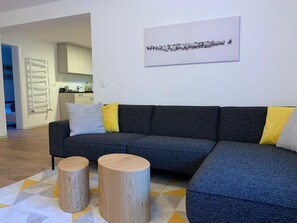 A modern living room with a grey sectional sofa, two wooden side tables, and a geometric patterned rug. - Perle "Balmhoru" # 5-bed apartment, Dusche, WC 5-Bettwohnung, Dusche, WC by Interhome (Leukerbad)