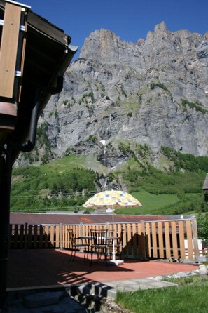Un patio con mobiliario exterior, un telón de fondo montañoso y cielo despejado.