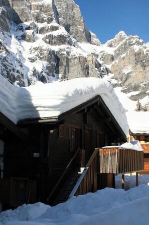 A wooden cabin with a staircase leading up to a porch, surrounded by snow-covered mountains. - Chalet Kondore 1 # 5-bed apartment, Dusche, WC 5-Bettwohnung, Dusche, WC by Interhome (Leukerbad)