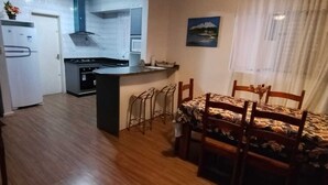 A compact living space with a kitchenette, dining area, and a view of the outdoors. - Vacation rental apartment in the center of Canasvieiras. (Florianópolis)