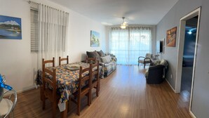 A dining area with a table and chairs, a sofa, and a chair. - Vacation rental apartment in the center of Canasvieiras. (Florianópolis)