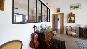 A room with a large mirror, a violin, a wooden cabinet, a chair, and a painting on the wall.