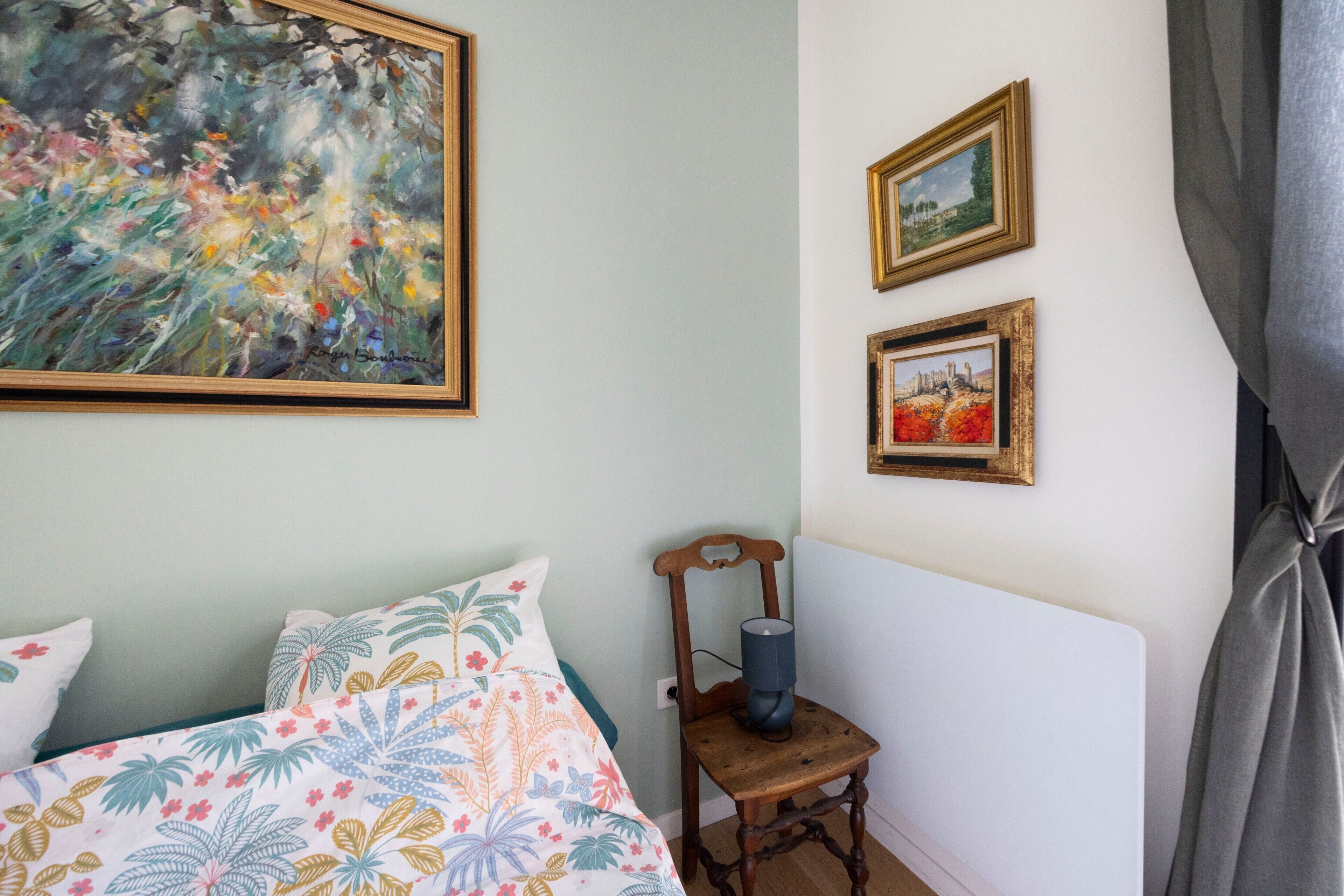 Ein Schlafzimmer mit einem Bett, einem Sessel und zwei gerahmten Bildern an der Wand.