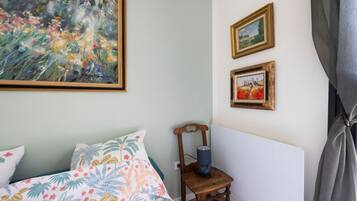 Ein Schlafzimmer mit einem Bett, einem Sessel und zwei gerahmten Bildern an der Wand.