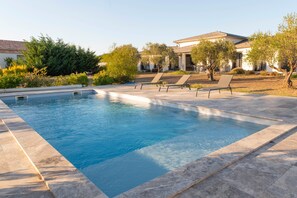 A rectangular swimming pool with lounge chairs, surrounded by a landscaped garden and a building with a tiled roof. - Room "Chambre 3" with Mountain View, Shared Pool and Wi-Fi (Aléria)