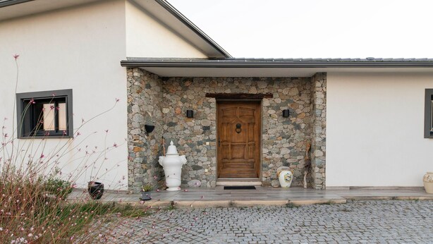 A building with a stone facade, a wooden door, and a small porch area.