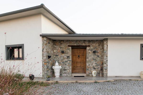 A building with a stone facade, a wooden door, and a small porch area.