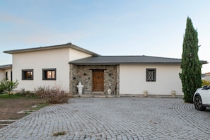 A modern house with a stone facade, a wooden door, and a cobblestone driveway.