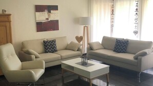 Ein modernes Wohnzimmer mit zwei Sofas, einem Couchtisch und einer Stehlampe.