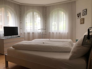 A bedroom with a bed, a desk with a computer, and curtains. - Edelweiss A 11 # 4-bed apartment, Dusche, WC 4-Bettwohnung, Dusche, WC by Interhome (Leukerbad)