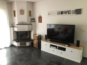 A modern living room with a flat-screen TV, a fireplace, and decorative wall art. - Edelweiss A 11 # 4-bed apartment, Dusche, WC 4-Bettwohnung, Dusche, WC by Interhome (Leukerbad)