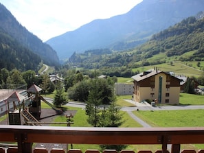 A mountain village with a playground, a building with a sloped roof, and a road winding through the valley. - Edelweiss A 11 # 4-bed apartment, Dusche, WC 4-Bettwohnung, Dusche, WC by Interhome (Leukerbad)