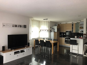 Una cocina moderna con comedor, televisor de pantalla plana y horno empotrado.