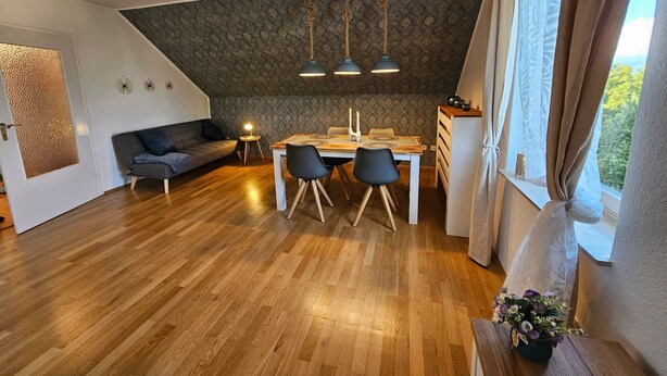 Ein moderner Wohnraum mit Essbereich, einer Couch und Blick durch ein Fenster.