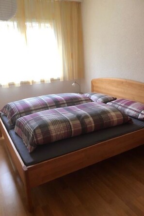 Ein Einzelbett mit Holzrahmen und einer karierten Bettdecke.