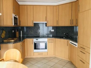 Eine kleine Küche mit Holzschränken, einer Mikrowelle, einem Backofen und einem Spülbecken.