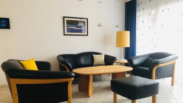 Ein modernes Wohnzimmer mit einer Sofagarnitur, einem Couchtisch und einer Lampe.