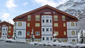 Ein mehrstöckiges Hotel mit roter und weißer Fassade, großen Fenstern und einem Berg im Hintergrund.
