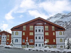 Ein mehrstöckiges Hotel mit roter und weißer Fassade, großen Fenstern und einem Berg im Hintergrund.