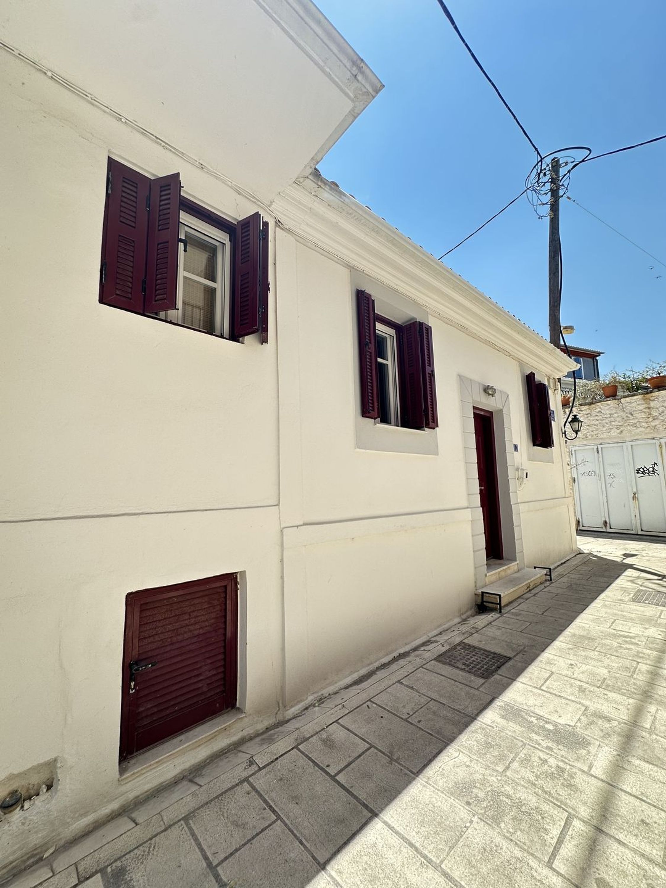 Un bâtiment à la façade blanche, aux volets rouges et à la petite entrée.