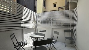 A small outdoor patio with a round table and four chairs, surrounded by white blinds. - Sapfous 10 (Lefkada)