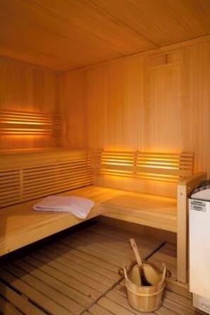 A wooden sauna with benches and benches, a wooden bucket, and a bench with a towel. - Ambassador B01 # 4-bed apartment, Dusche und Bad, WC by Interhome (Leukerbad)