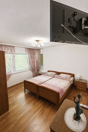 Ein Schlafzimmer mit einem hölzernen Bett, einem Nachttisch, einer Kommode und einem an der Decke befestigten Fernseher.
