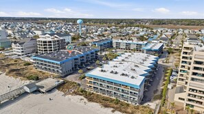 A coastal hotel with multiple buildings, a water tower, and a beach area. - Surf Shack at Sea Cabin w Pool (North Myrtle Beach)