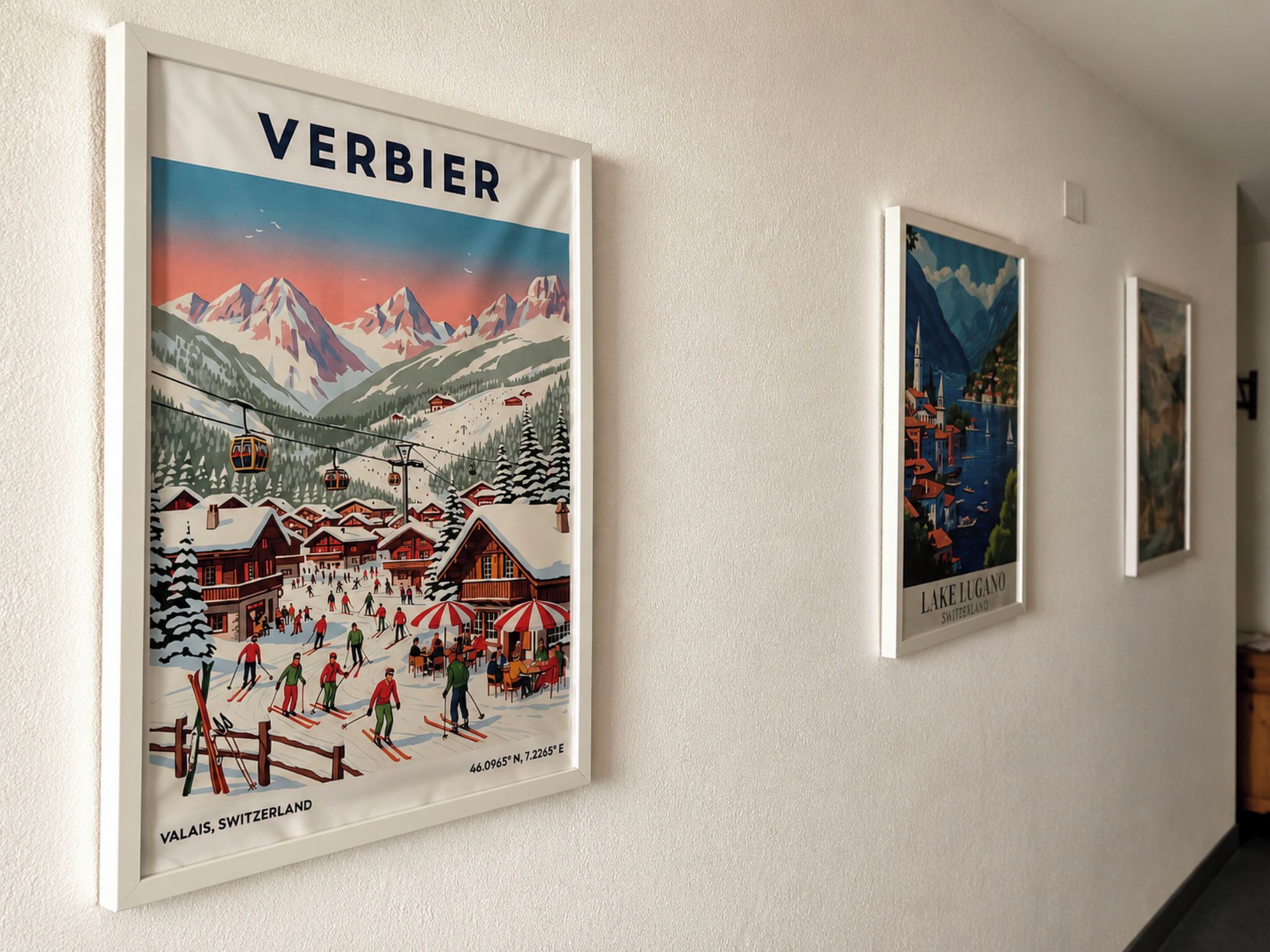Eine Wand mit gerahmten Postern aus Wallis, Schweiz, darunter eine Szene vom Skigebiet und eine Seeblickansicht.