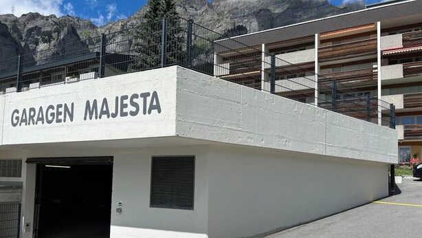 Einfahrt einer Parkgarage mit der Beschriftung 'GARAGEN MAJESTA', mit einer Betonfassade und einem Metallgeländer.
