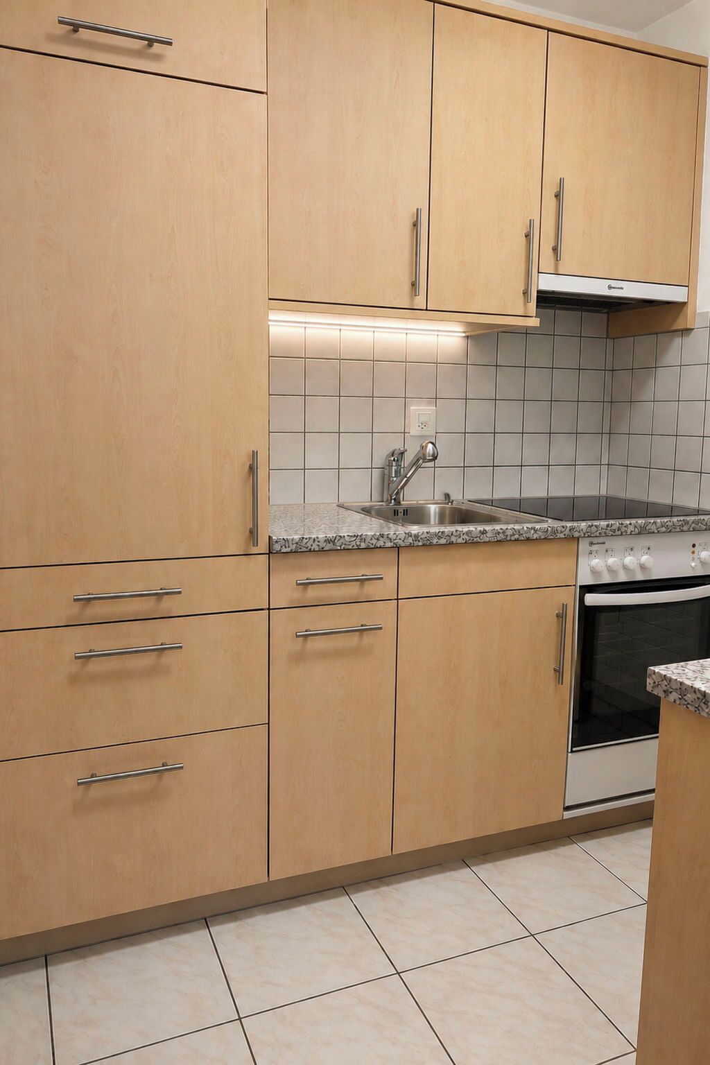 A kitchen with wooden cabinets, a stainless steel sink, and a built-in oven.