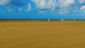 Una playa con cielo despejado y algunos veleros.
